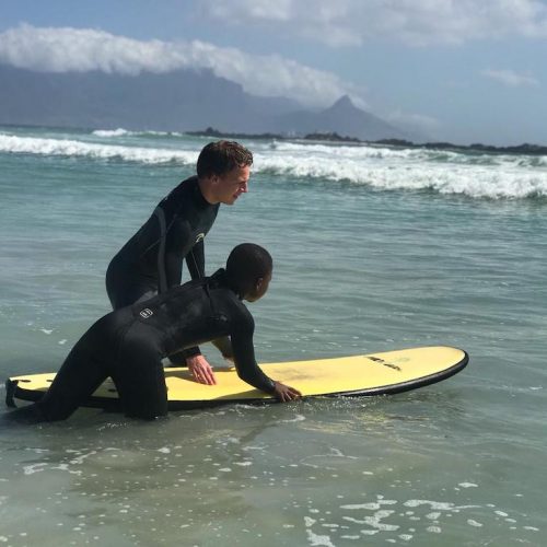 Coach de kinderen in Zuid-Afrika met surflessen